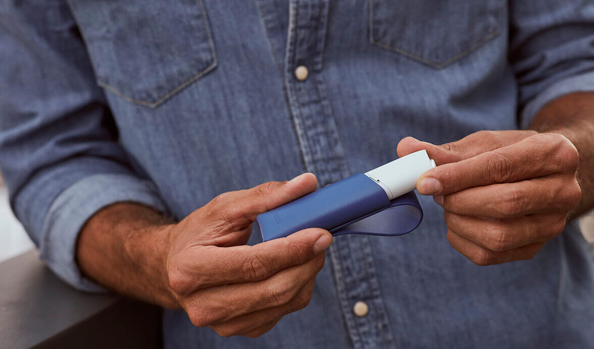 Mano de hombre con Kit IQOS 3 MULTI blanco y funda azul