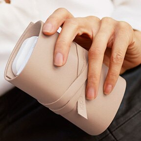 Mano de mujer con funda de piel enrollable color crema