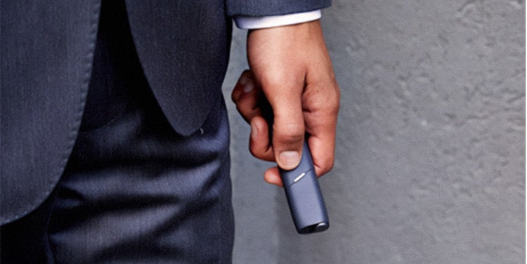 A man holds an IQOS device