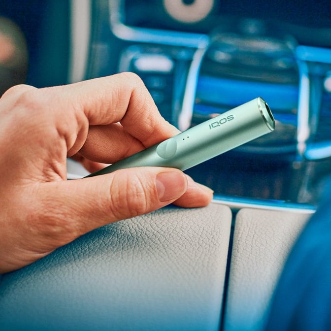 An IQOS ILUMA device in a person's hand.