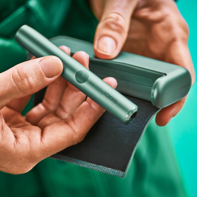 A hand removing a Holder from an IQOS ILUMA Pocket Charger.