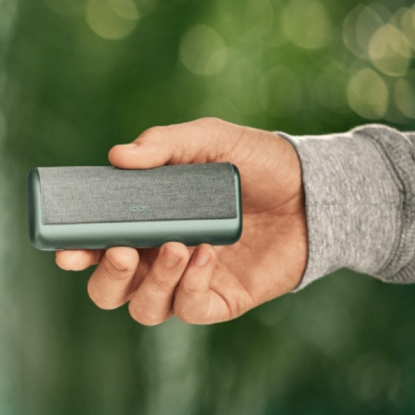 A Jade Green IQOS ILUMA PRIME Holder and Pocket Charger in a person's hands.