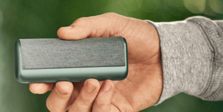 A Jade Green IQOS ILUMA PRIME Holder and Pocket Charger in a person's hands.