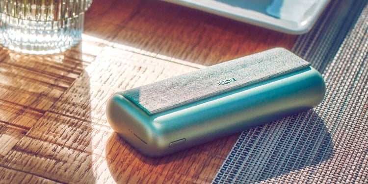 A Jade Green IQOS ILUMA PRIME Pocket Charger on a table.