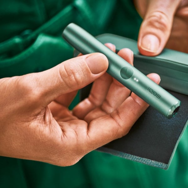 An IQOS ILUMA PRIME Holder in a person's hands, the lights visible.