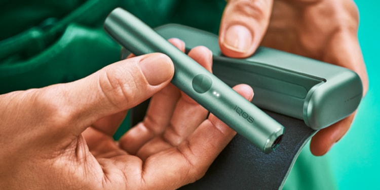 An IQOS ILUMA PRIME Holder in a person's hands, the lights visible.