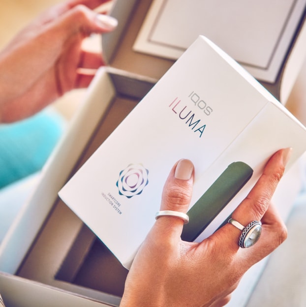 A person opening a box containing a new IQOS ILUMA.