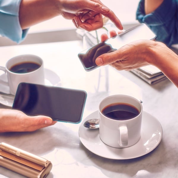 Two people with mobile phones having coffee.