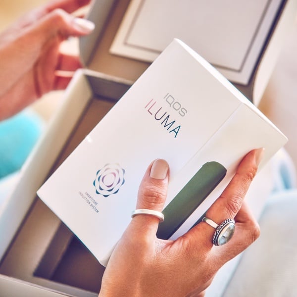 A person holding an IQOS ILUMA box.