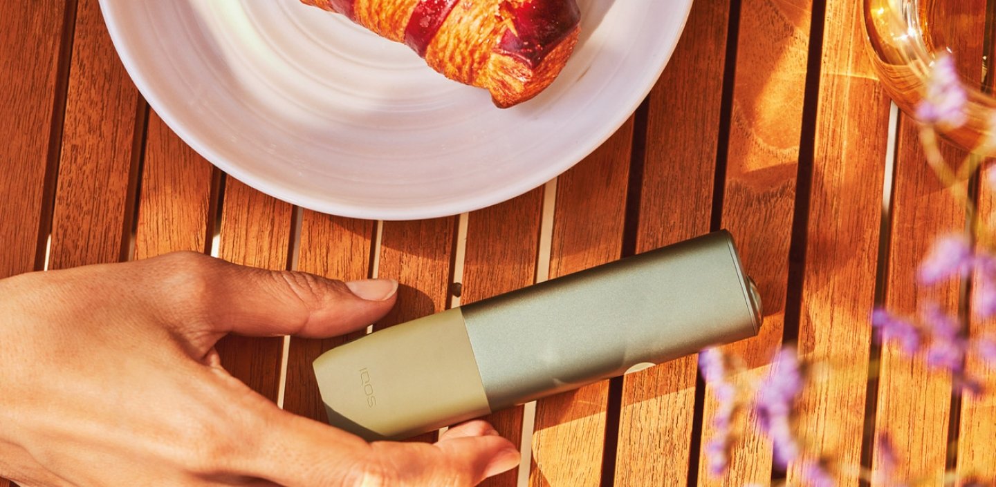 Dispositivo IQOS ILUMA ONE sobre una mesa de madera