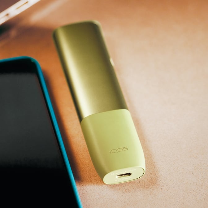 IQOS ILUMA ONE junto a un dispositivo móvil y un ordenador portátil