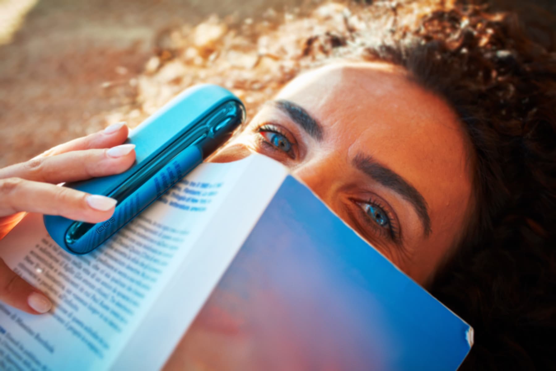 Chica con un libro y dispositivo IQOS