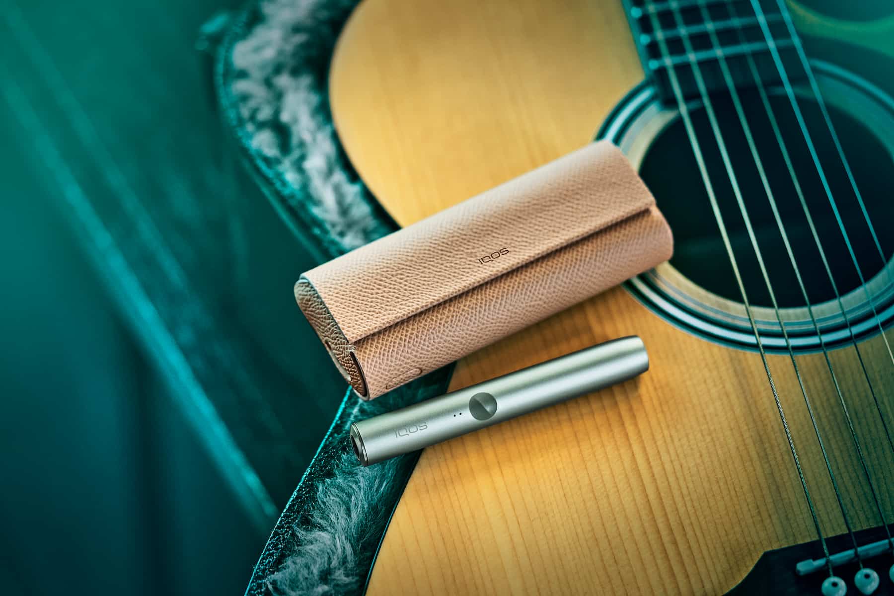Dispositivo IQOS ILUMA PRIME con una guitarra