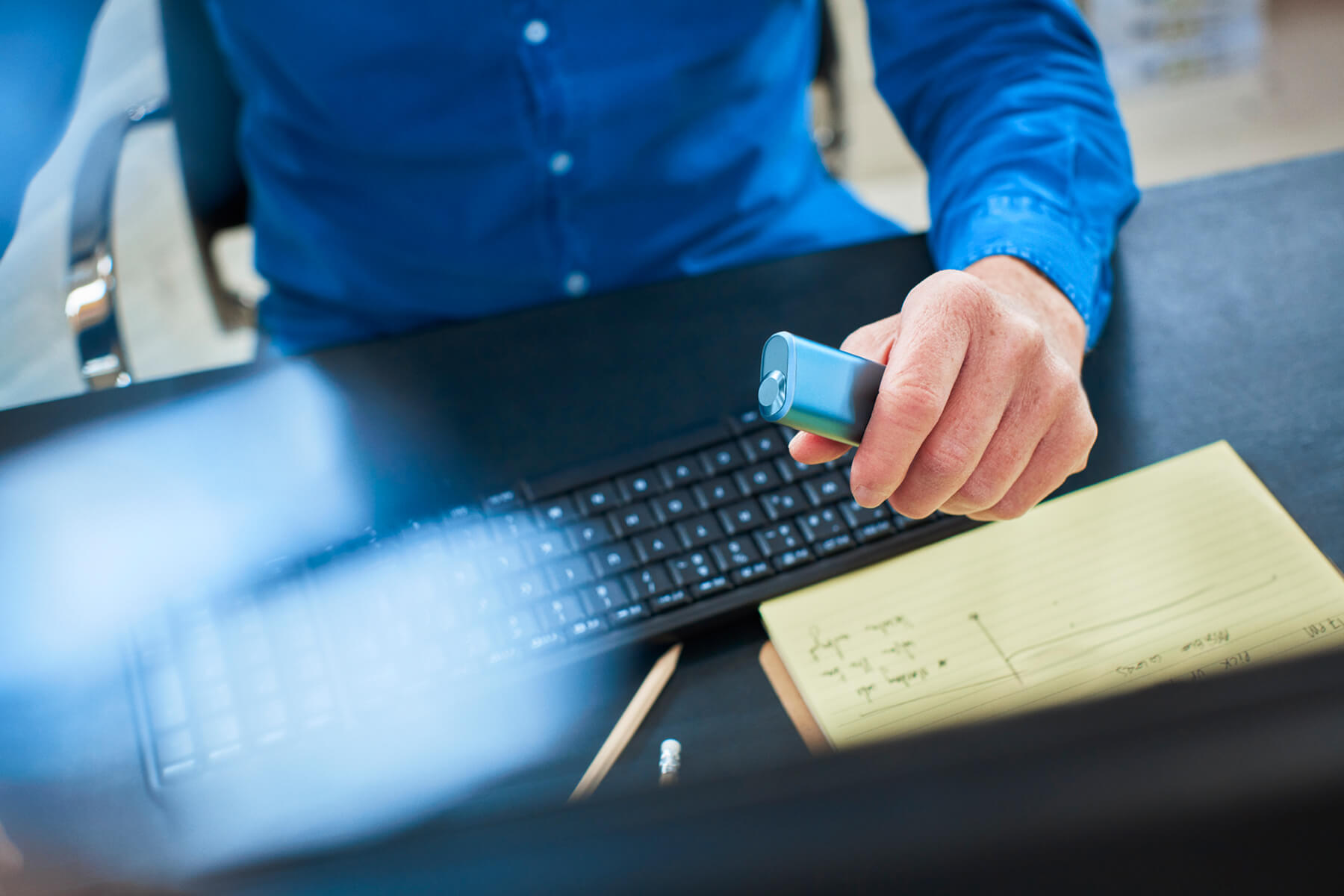 Usuario en escritorio con dispositivo IQOS en la mano