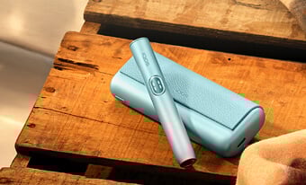 Dispositivo IQOS ILUMA i sobre una mesa de madera
