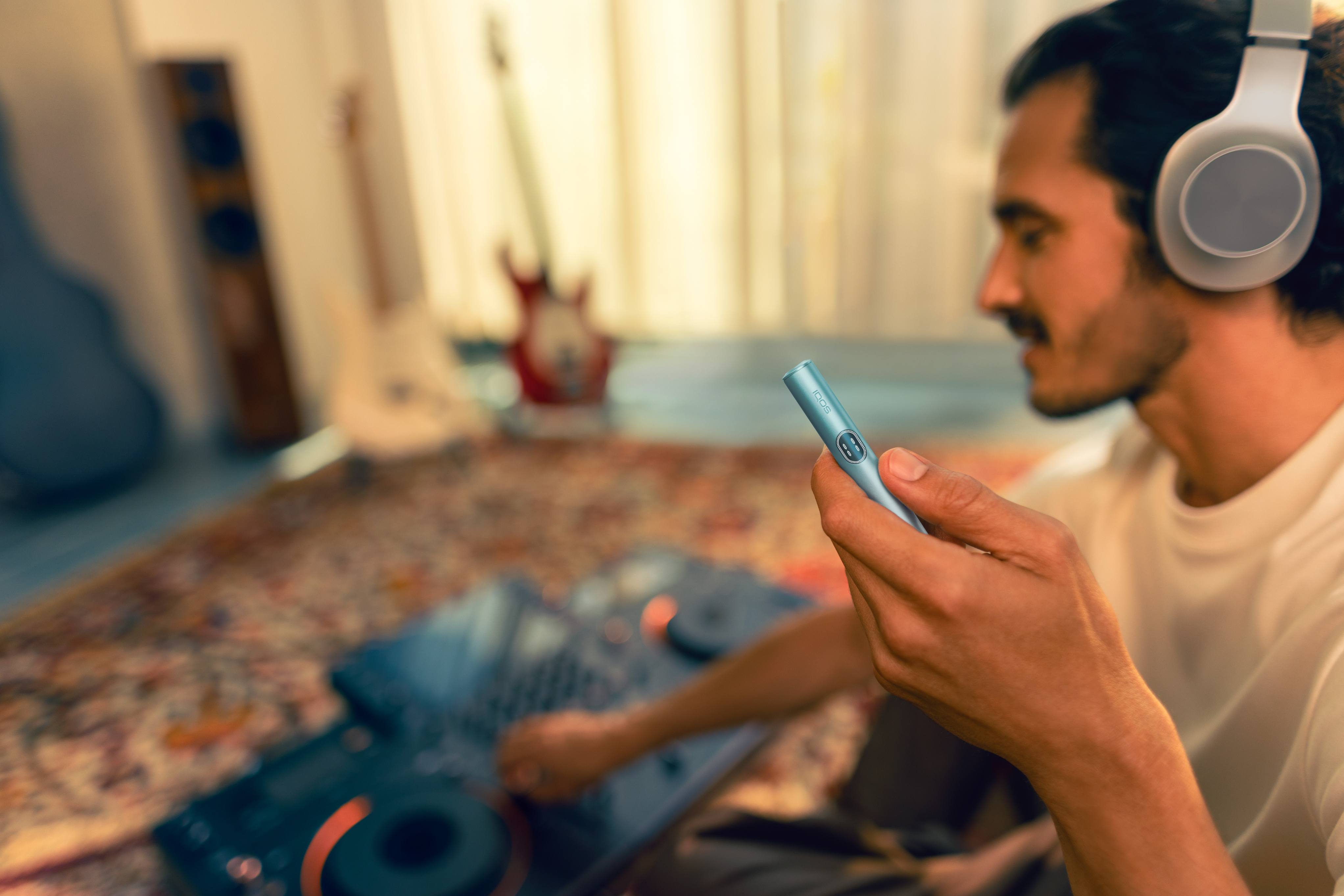 Hombre escucha música con holder IQOS ILUMA i en la mano