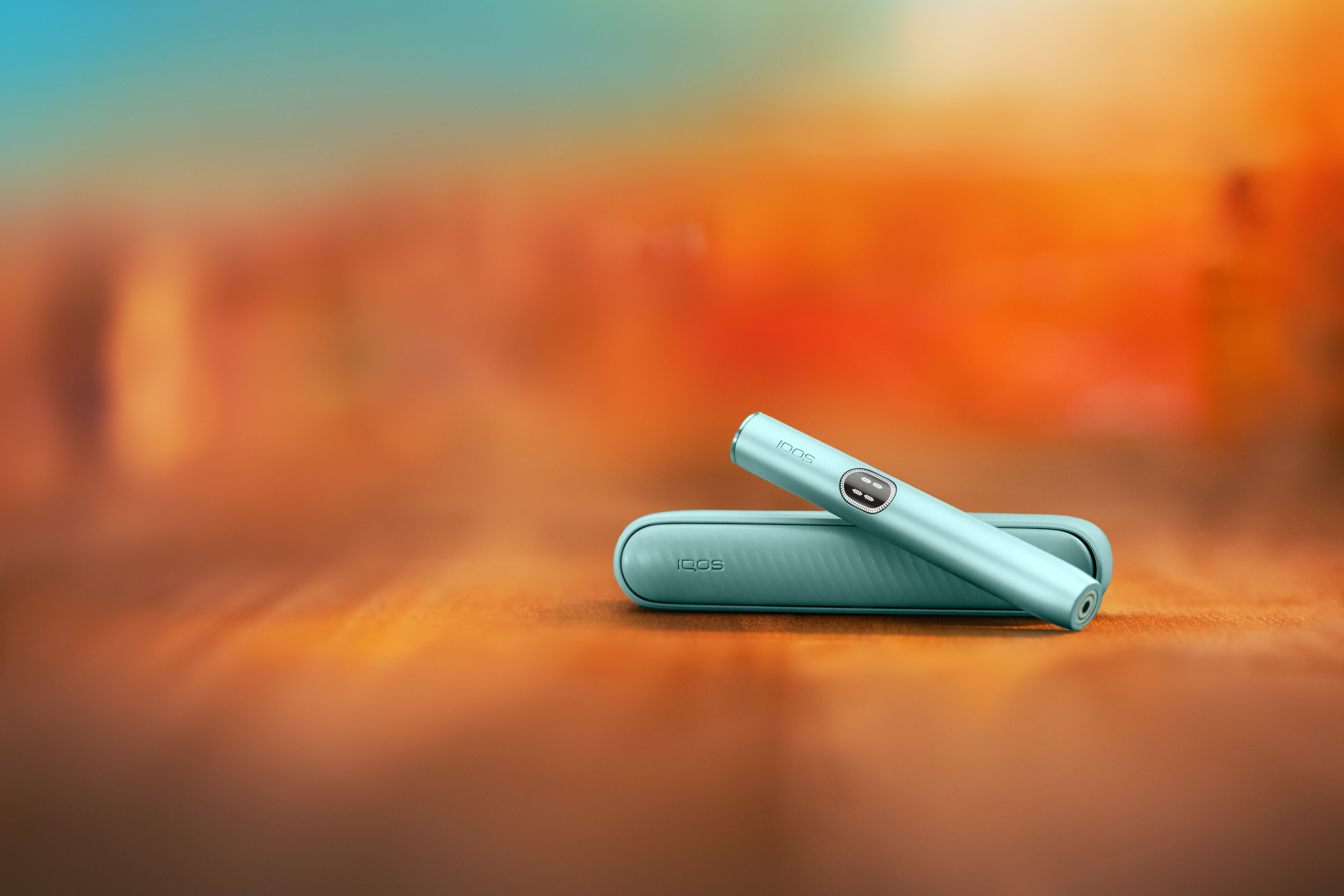 Dispositivo IQOS ILUMA i Azul Brisa sobre fondo naranja