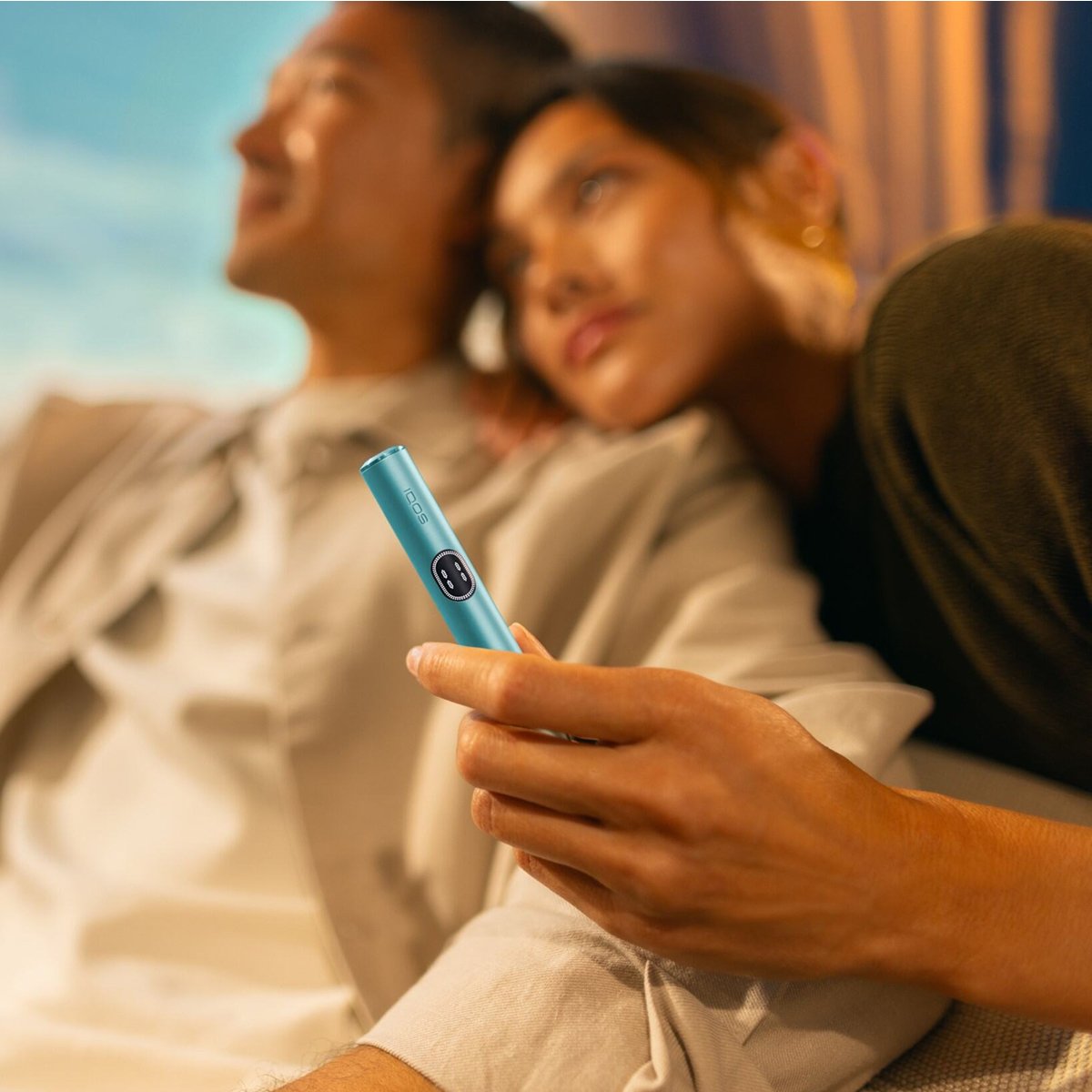 Dos personas abrazadas mientras uno porta un dispositivo IQOS