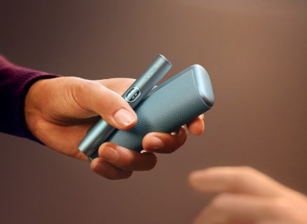 Mano sujetando cargador de bolsillo y holder de IQOS ILUMA i PRIME en Azul Brisa