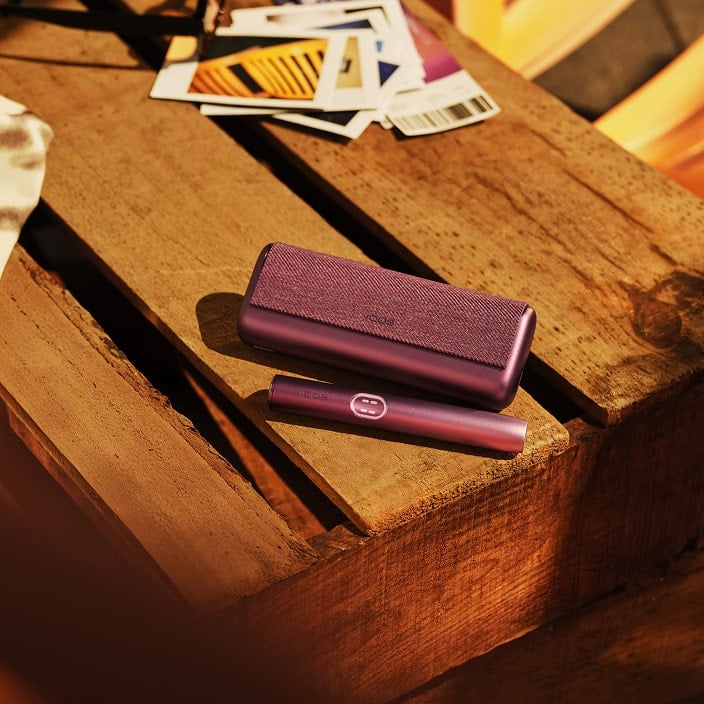 Dispositivo IQOS ILUMA i Prime Rojo Granate en una mesa de madera