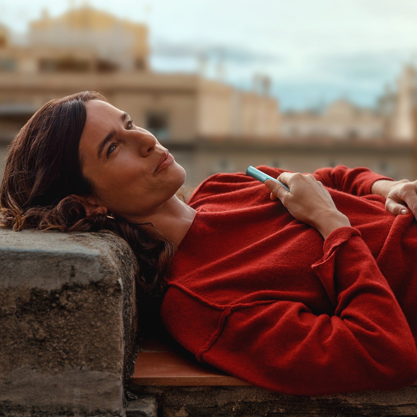 Mujer con jersey rojo sujetando el holder de IQOS ILUMA i