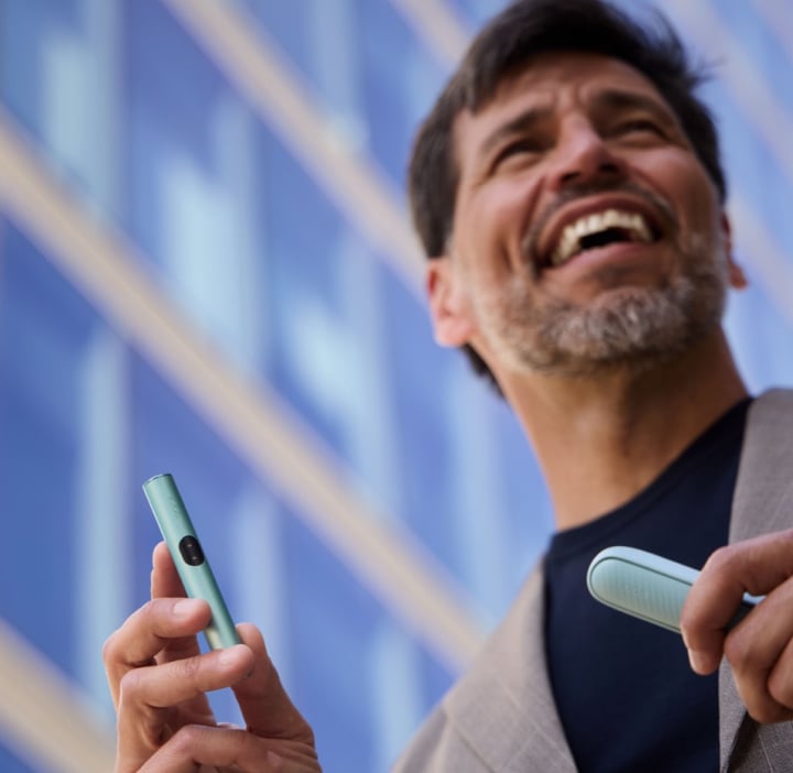 Un hombre sostniendo un IQOS ILUMA I mientras sonrie