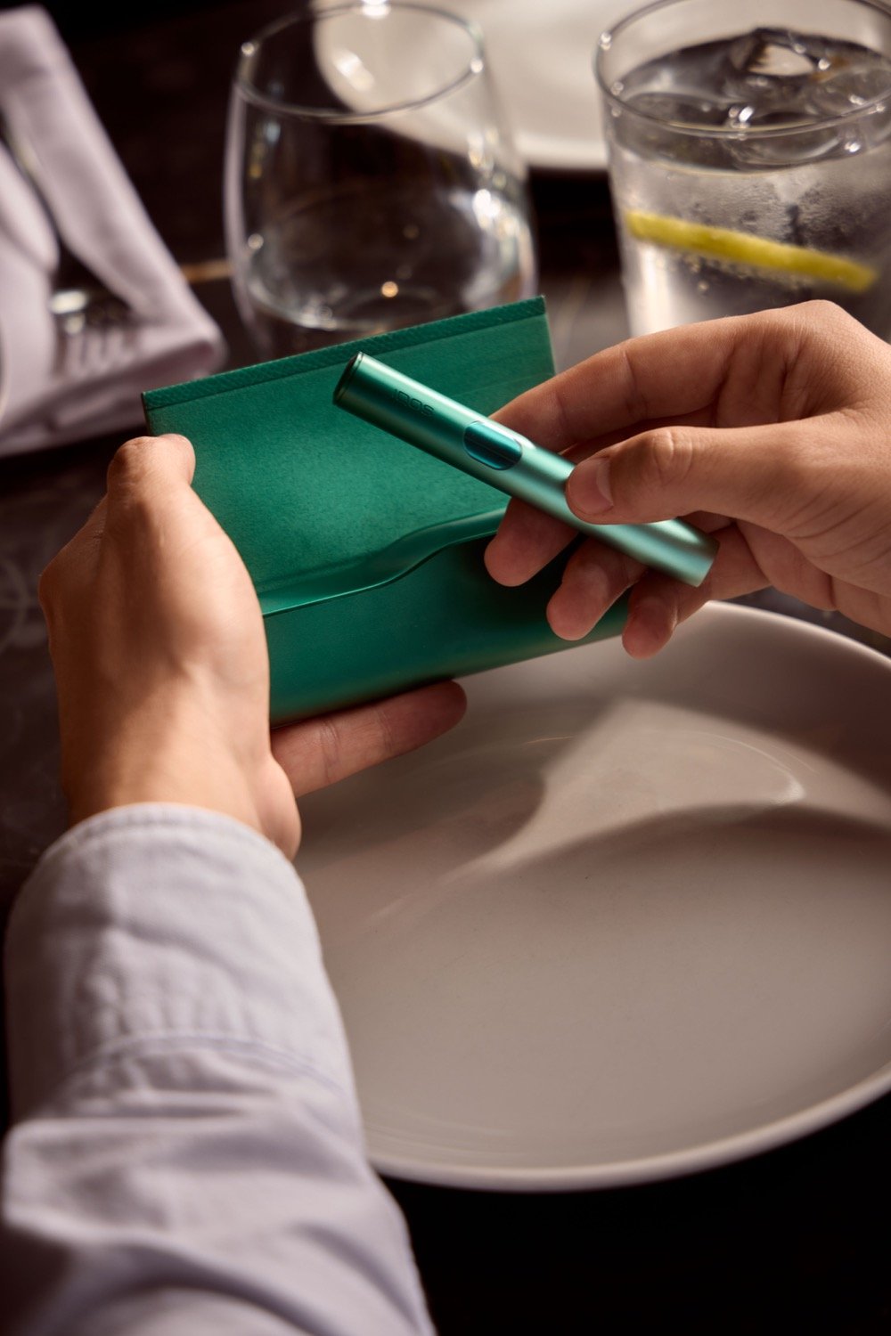 Manos sujetando un IQOS ILUMA I Verde