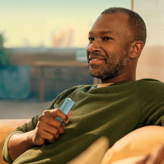 Persona mirando al horizonte mientras ríe con su dispositivo IQOS en la mano