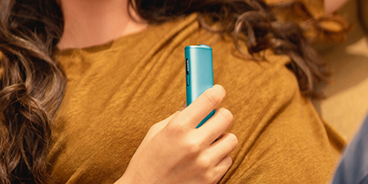 Mano de una mujer sosteniendo dispositivos IQOS ILUMA I ONE