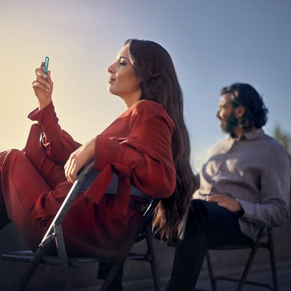 Mujer y hombre en una terraza con un holder de IQOS ILUMA i en la mano