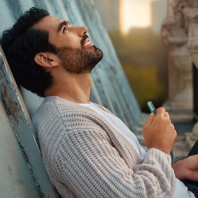 Hombre con holder de IQOS ILUMA i en una azotea