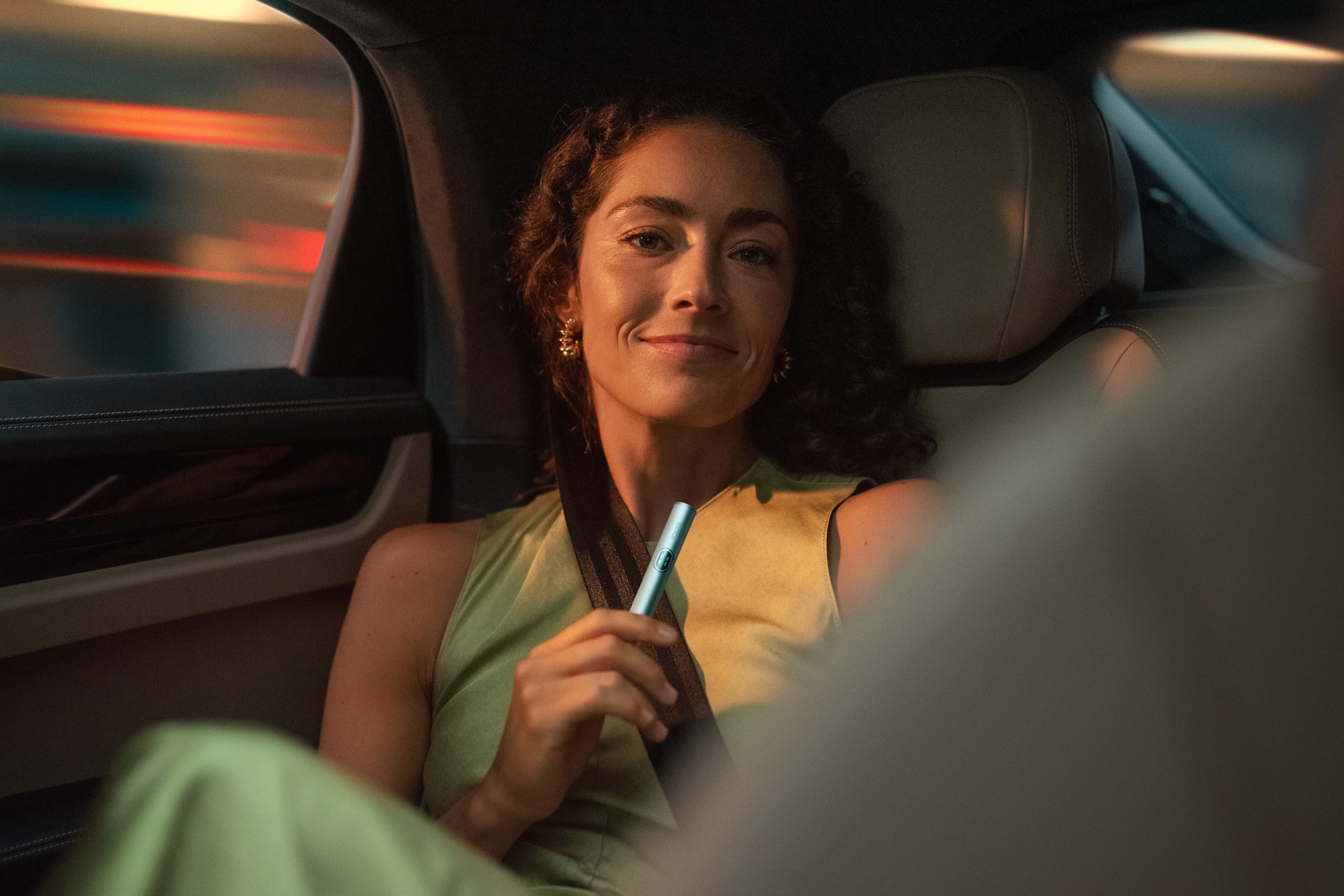 Mujer en un coche con holder de IQOS ILUMA i PRIME en azul brisa