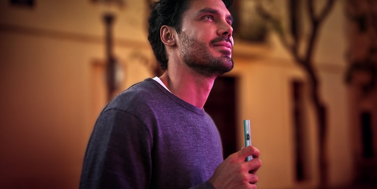 Hombre solo por la noche con un IQOS ILUMA i