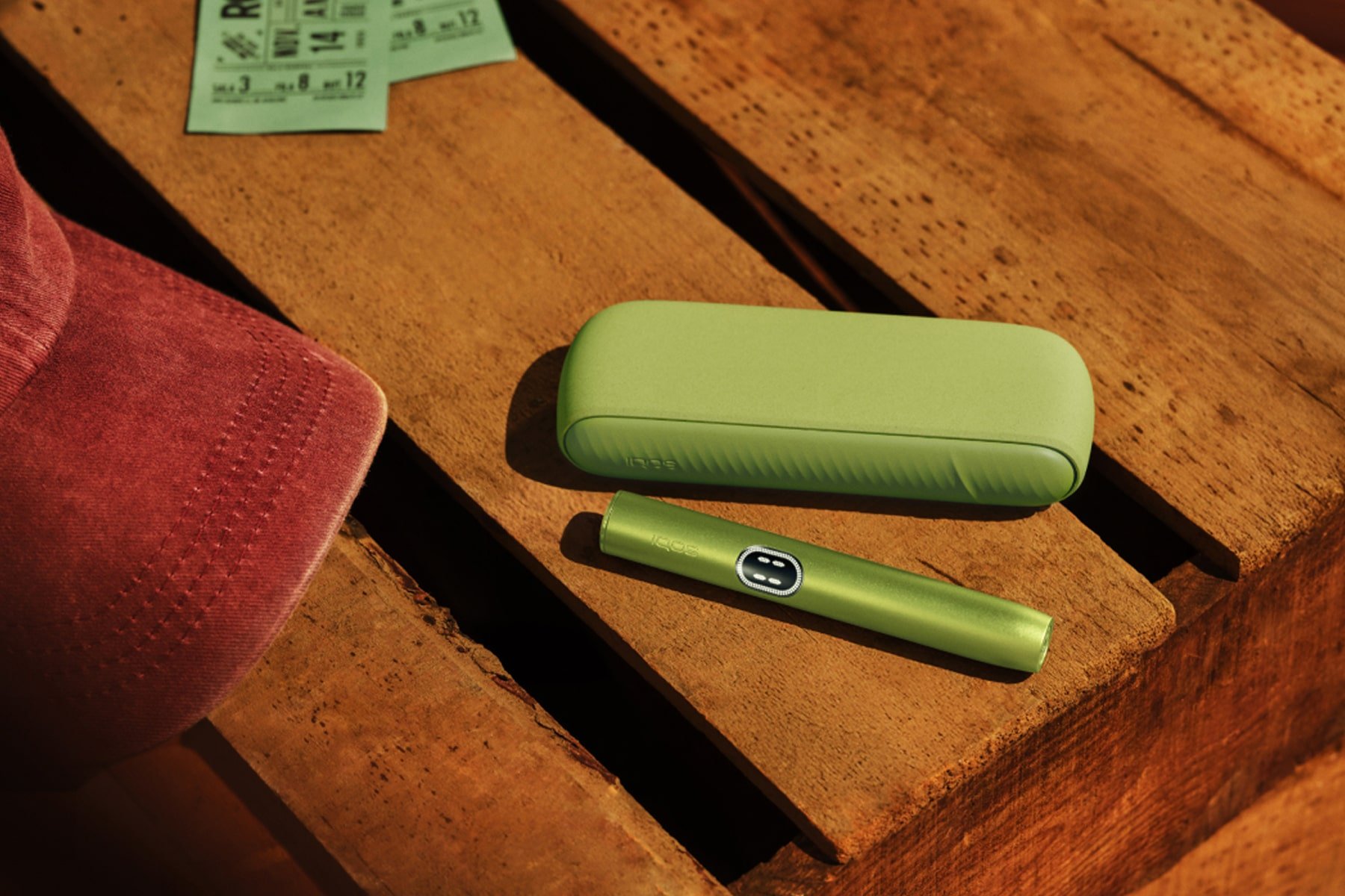 IQOS ILUMA i en Verde Hoja en una mesa de madera