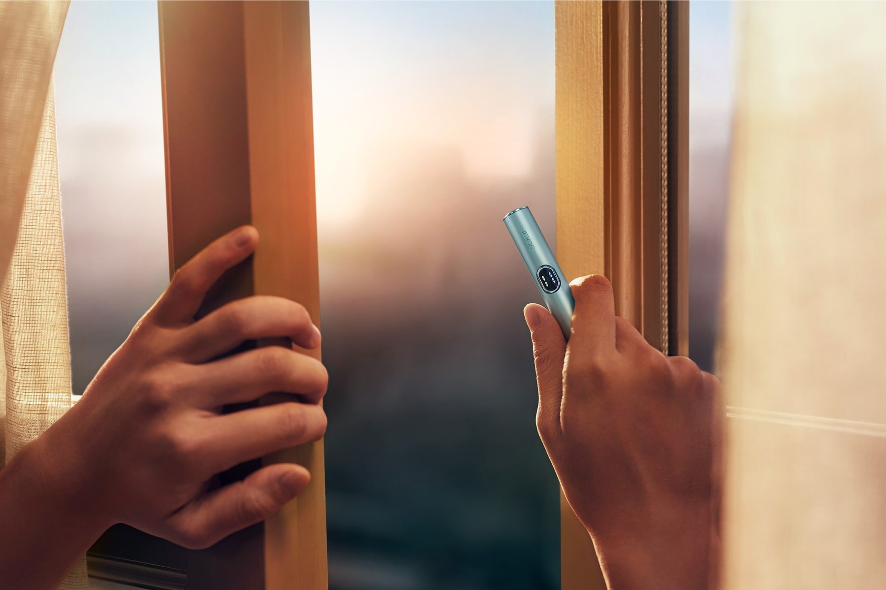 Dos manos abriendo una ventana con holder de IQOS ILUMA i