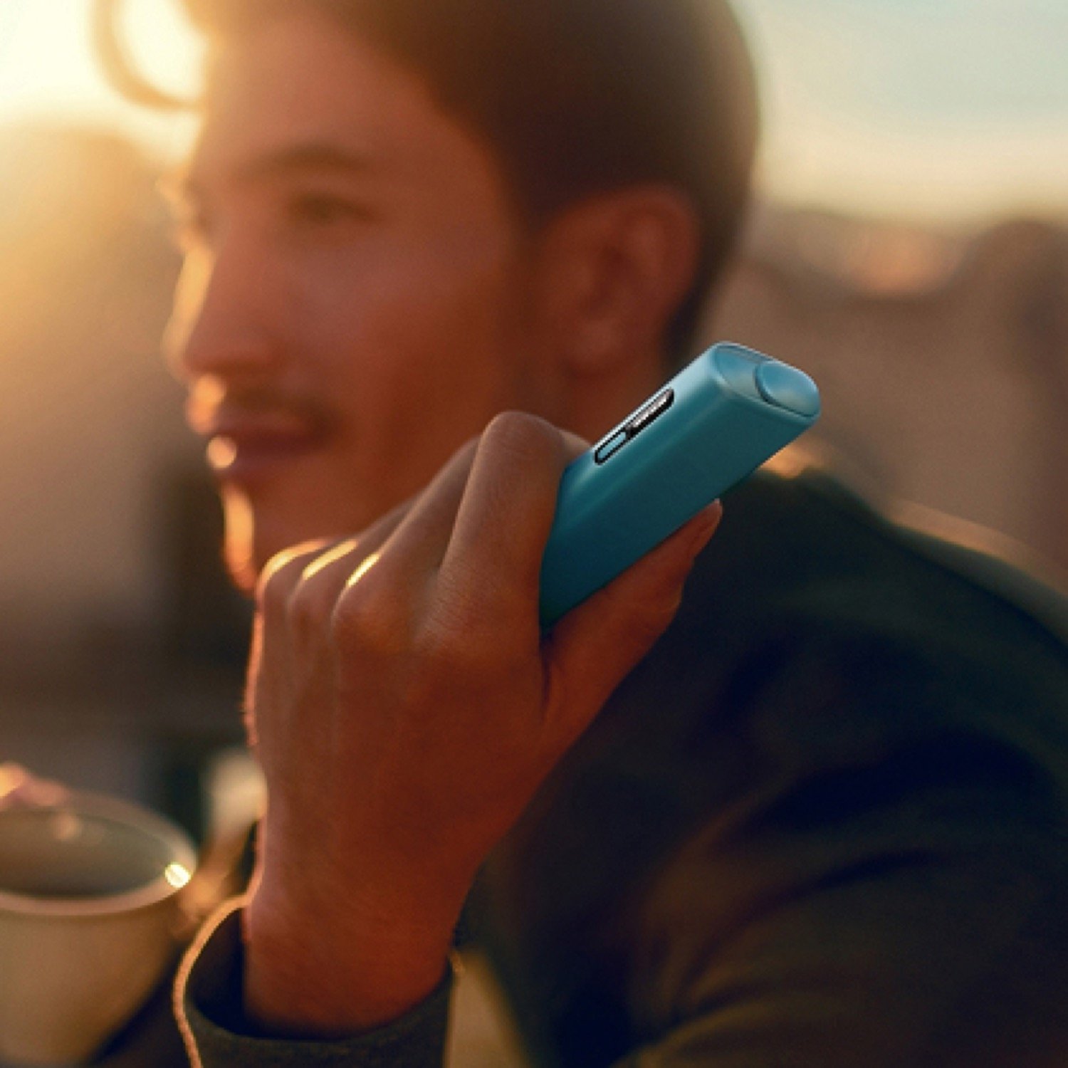 Un hombre sosteniendo un IQOS ILUMA I mientras mira al horizonte