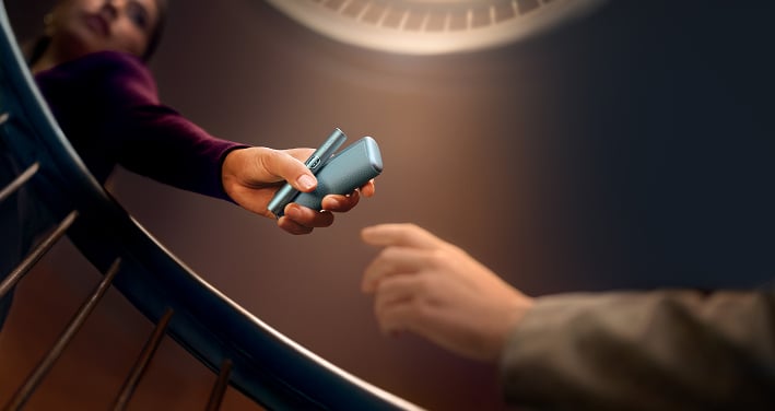Mujer entregando un IQOS ILUMA i