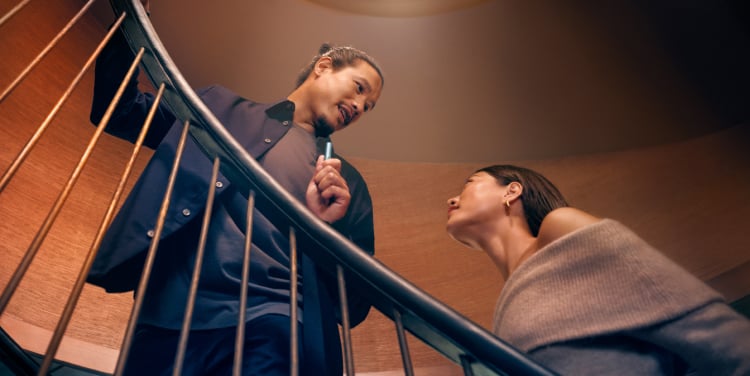 Hombre y mujer hablando en una escalera con IQOS ILUMA i