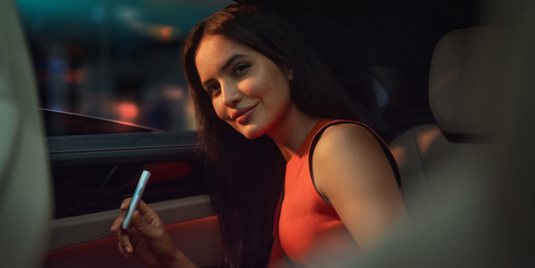 Señora sujetando un IQOS ILUMA i en un coche