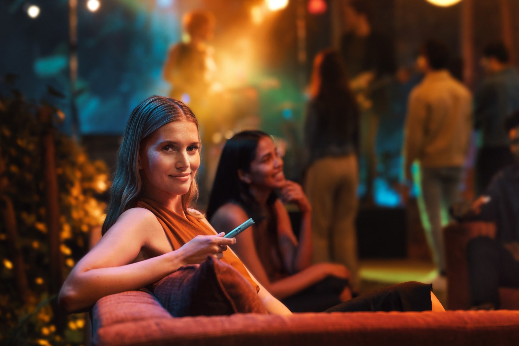 Chica con un IQOS ILUMA i sentada en sofá