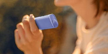 Mujer sujetando IQOS ILUMA i ONE en color lavanda