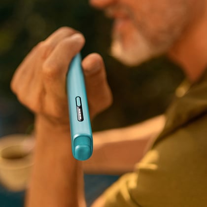 Un hombre sosteniendo un IQOS ILUMA I mientras sonríe