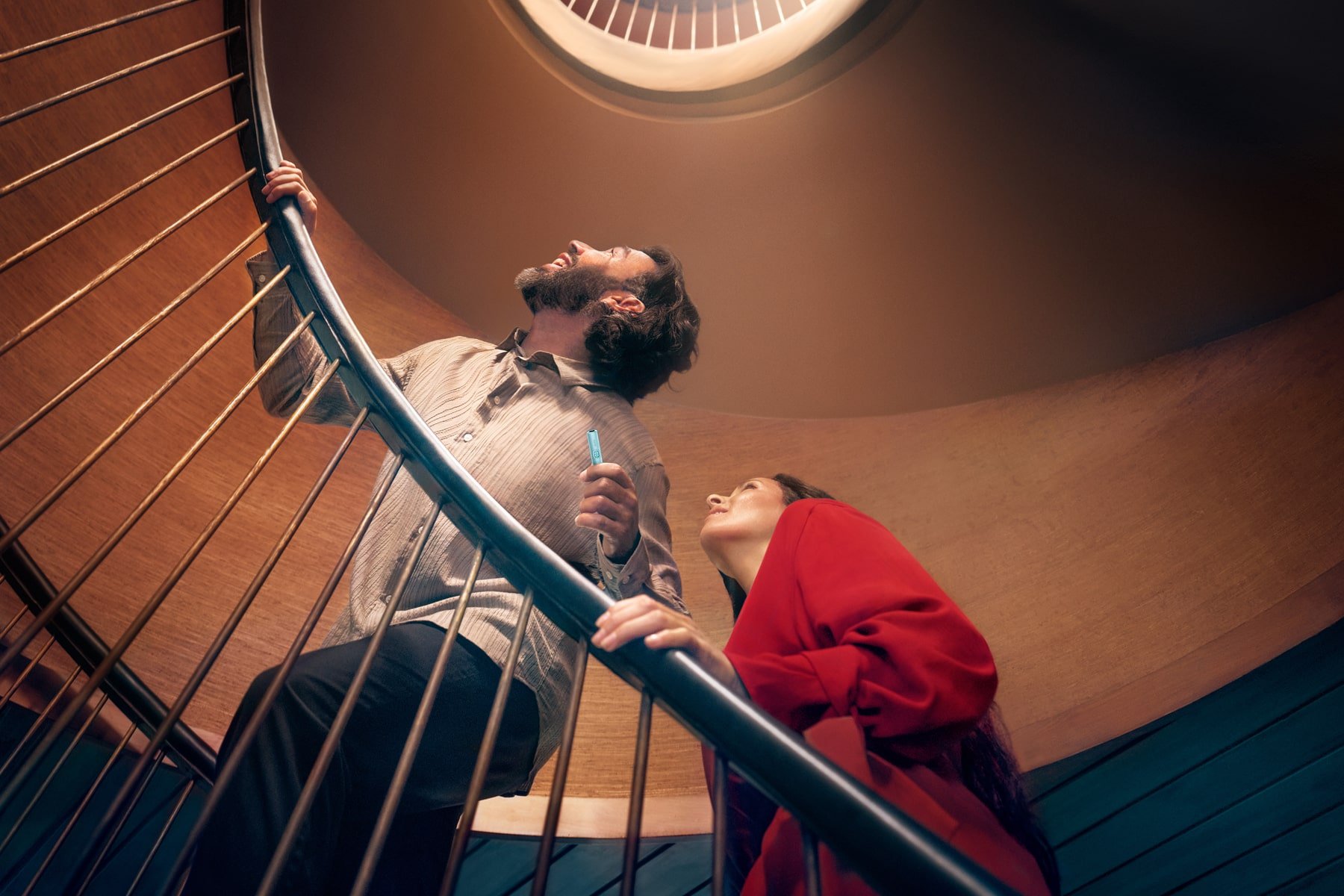 Hombre y mujer subiendo unas escaleras con el holder de IQOS ILUMA i PRIME en la mano
