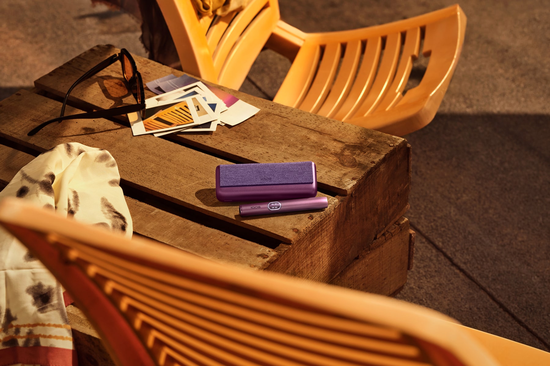Dispositivo IQOS ILUMA i PRIME Rojo Granate sobre una mesa de madera