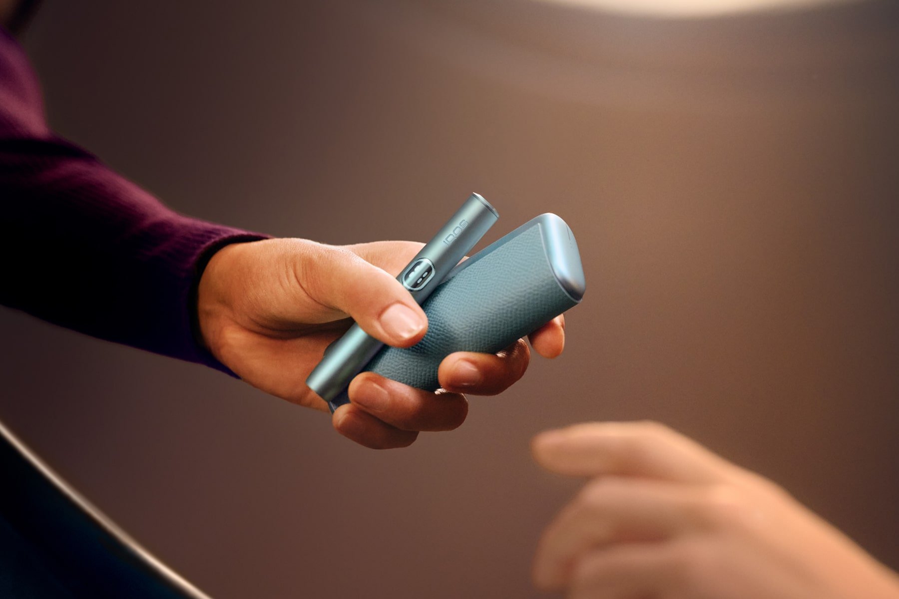Mano sujetando IQOS ILUMA i PRIME en azul brisa