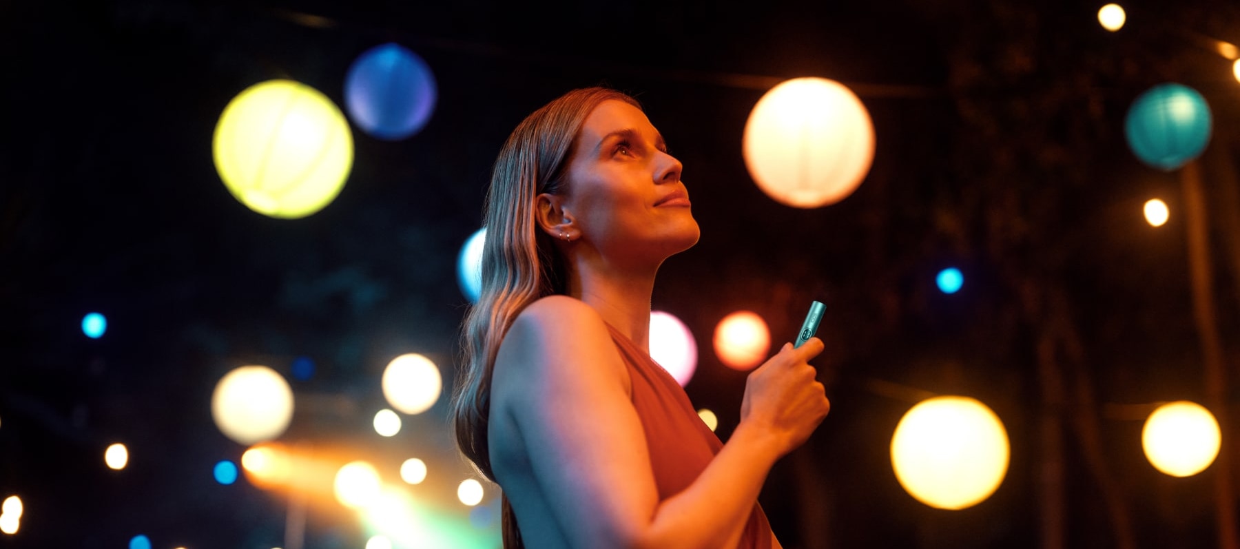 Chica con IQOS ILUMA i con luces de fondo