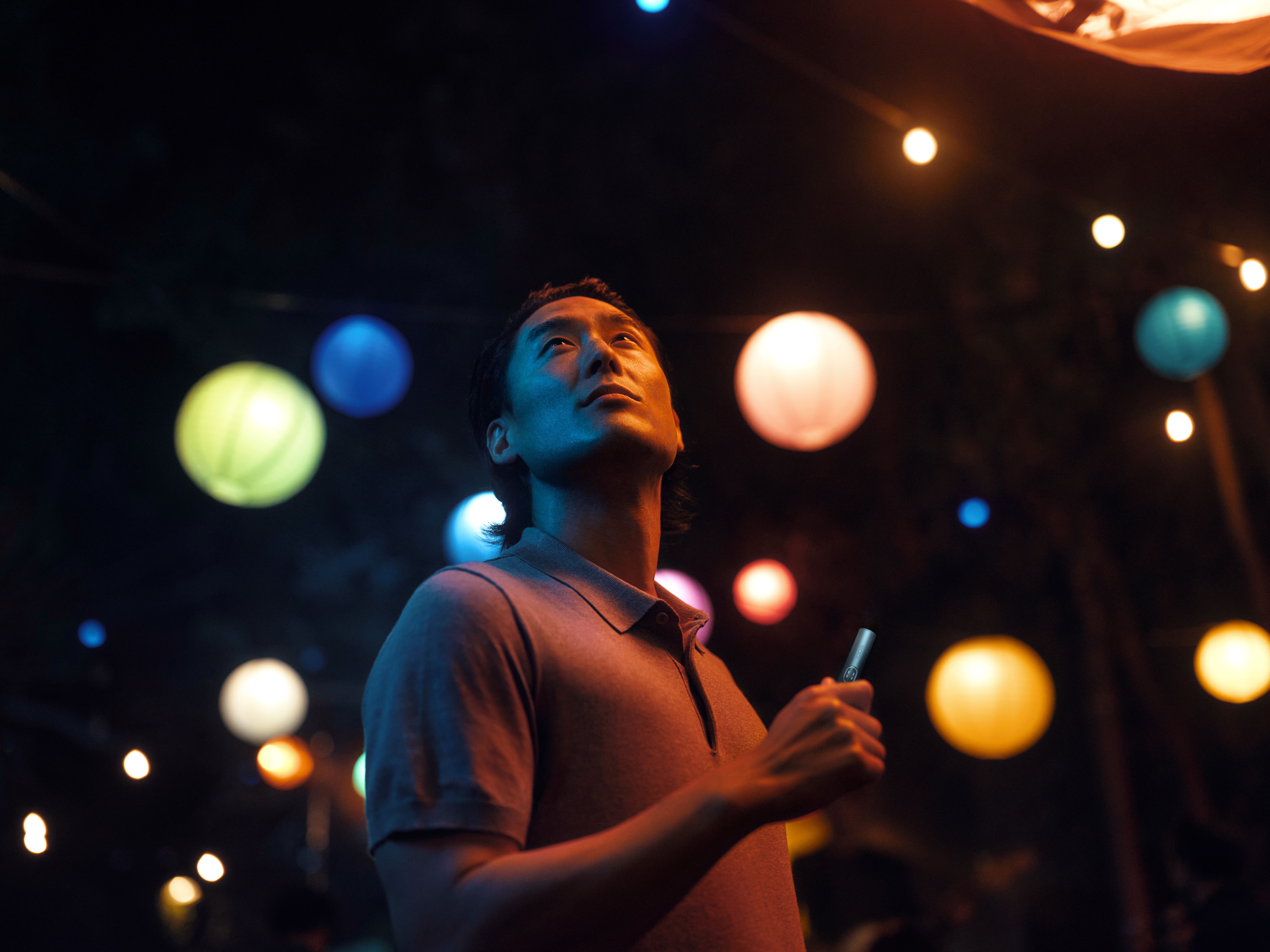 Hombre con un iqos y luces detrás
