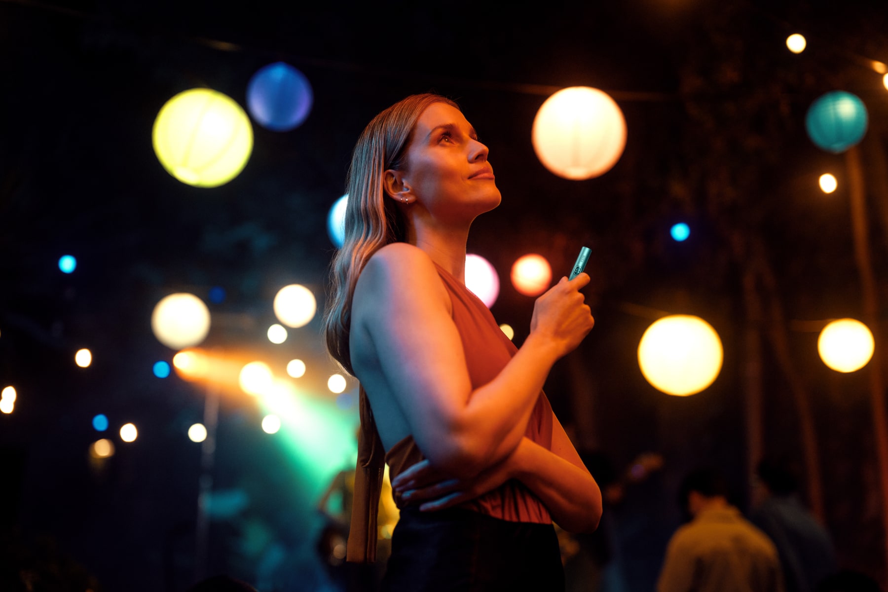 Chica con IQOS ILUMA i y luces de fondo