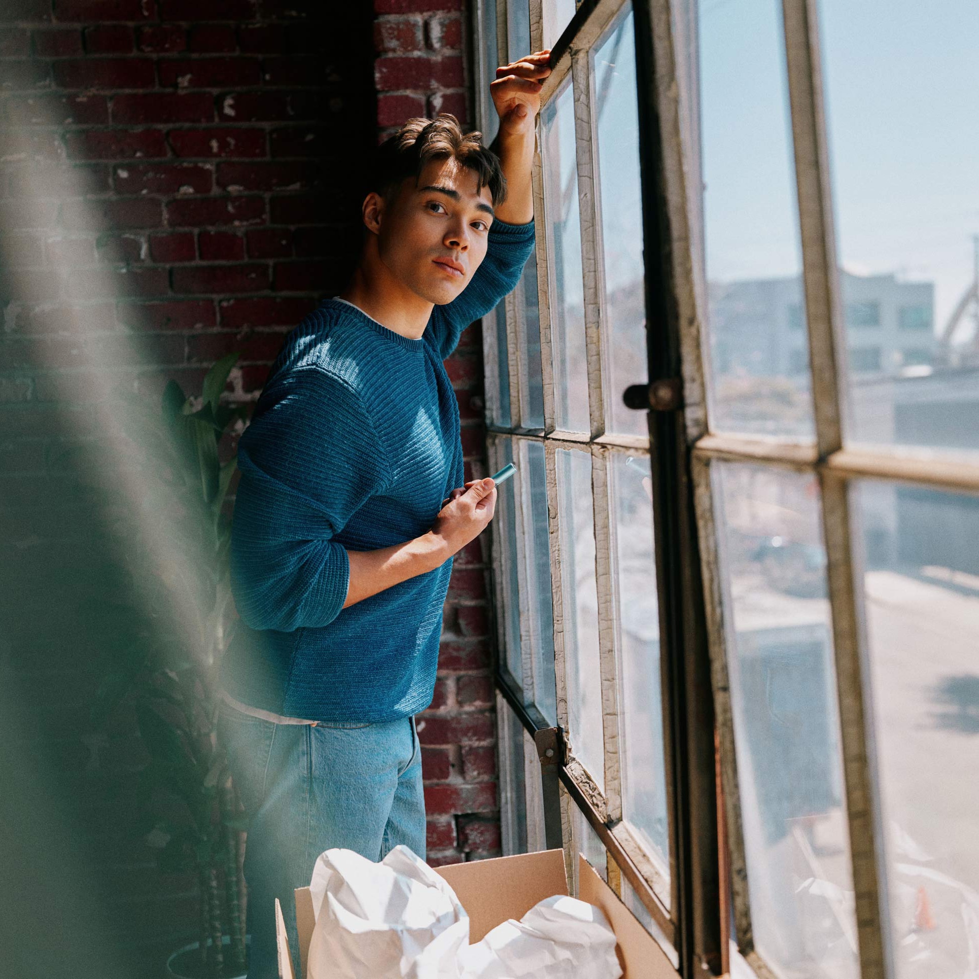 Usuario de IQOS mirando por la ventana con su dispositivo IQOS ILUMA i