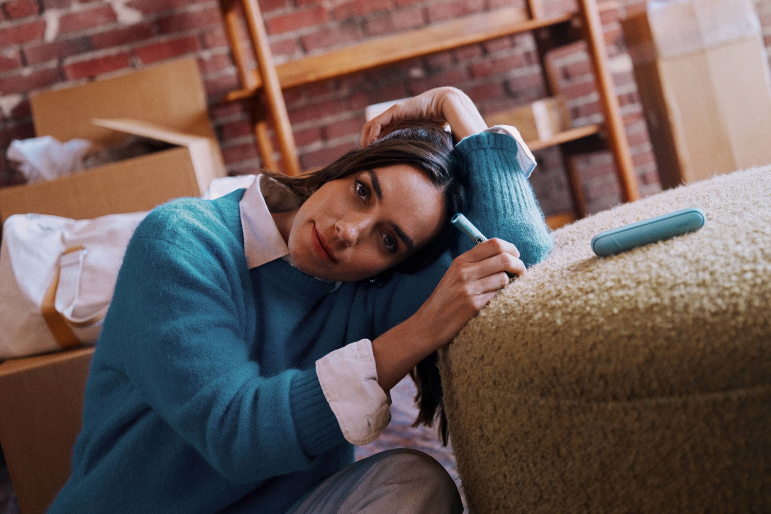 Mujer apoyada en sofa con iqos iluma i en la mano